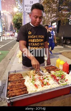 Los Angeles, CA, USA. Oktober 2020. Ein lokaler Lebensmittelhändler trägt ein Hemd, das während eines Protestes gegen China ausgehändigt wurde, und einen Stand in Solidarität mit den Demonstranten in Hongkong. Ein Mann, der unter dem Pseudonym Sun dazukommt, organisierte die Veranstaltung, bei der im Staples Center Hemden zur Unterstützung der Demonstranten aus Hongkong verteilt wurden. Stockfoto