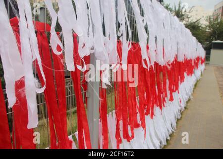 MINSK, WEISSRUSSLAND - 2. September 2020: Die Flagge Weißrussland, die aus Bändern auf dem Zaun des Hofes gemacht ist. Weiß rot weiß Stockfoto