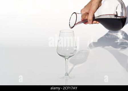 Sommelier gießt Rotwein von Dekanter bis Weinglas auf weißen Hintergrund. Stockfoto