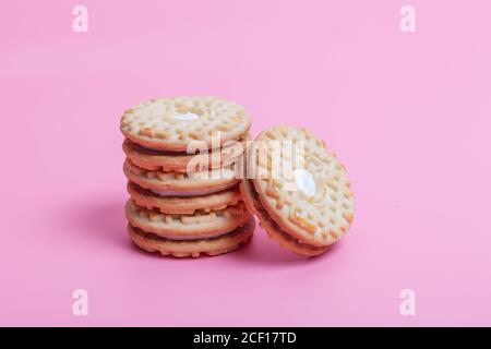 Cremefarbene Sandwich-Kekse auf rosa Hintergrund Stockfoto