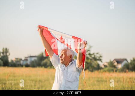 Flagge von Kanada, Nationales Symbol winkt gegen, sonniger Tag. Kanada Flagge in Senior man Hand. Selektiver Fokus Stockfoto