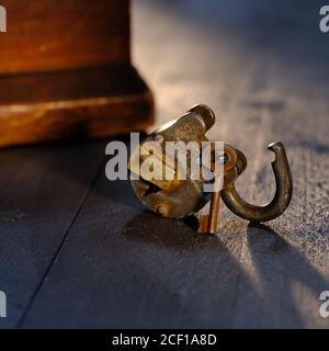 Trusty Vorhängeschloss mit Schlüssel auf weatehered texturierte Holztischplatte Stockfoto