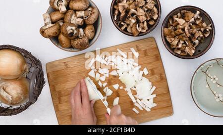 Koch hackt Zwiebel auf Holzschneidebrett, Nahaufnahme von oben Stockfoto