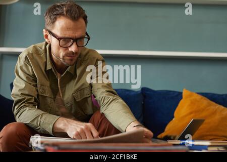 Seriöse Designer in Brillen sitzen am Tisch und arbeiten Mit Proben Stockfoto