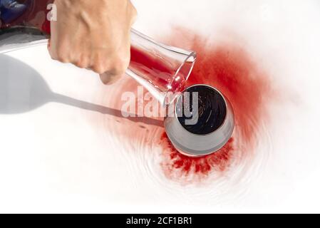 Sommelier gießt Rotwein von Dekanter bis Weinglas auf weißen Hintergrund. Stockfoto