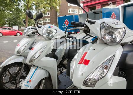 Eine Reihe von Pizzakurier vor einem Domino's Fast Food Delivery Restaurant, London, Großbritannien Stockfoto