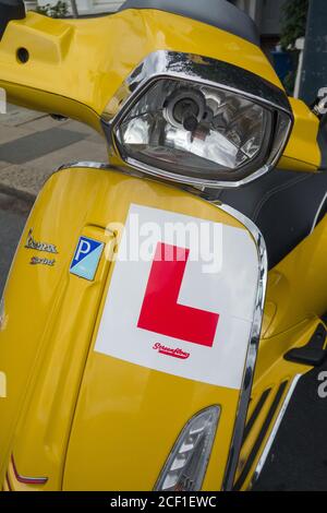 L Teller auf einer ikonischen, gelben Vespa Piaggio Sprint Stockfoto