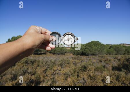 Nahaufnahme der Hand einer Person, die einen Kompass mit hält Ein Feld im Hintergrund Stockfoto