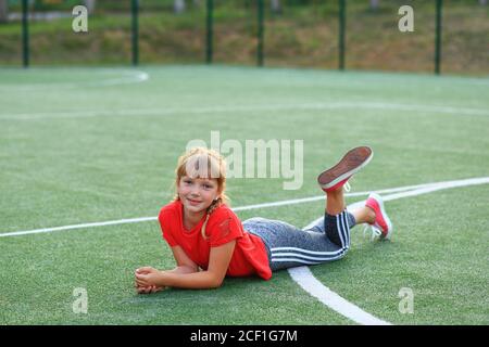 Mädchen in einem roten T-Shirt ist in der Gymnastik auf dem Sportplatz beschäftigt. Stockfoto