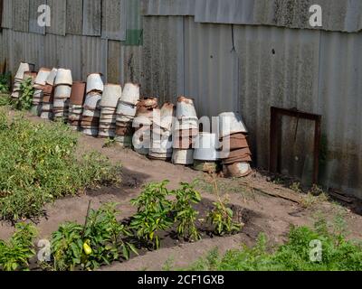 Stapel von vielen alten rostigen, undichten Eimern entlang der Schieferwand im Garten. Hochwertige Fotos Stockfoto