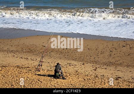 Ein Seeangler, der vom Strand an der Nord-Norfolk-Küste in Happisburgh, Norfolk, England, Großbritannien angeln kann. Stockfoto