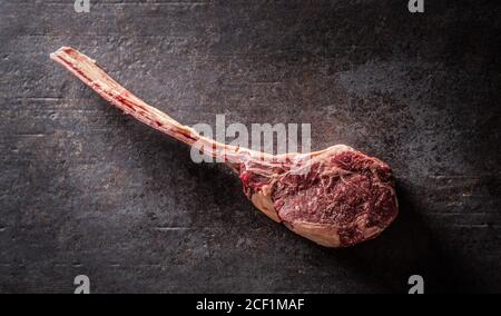 Rohes Tomahawk Steak auf einem alten rustikalen Brett - von oben gesehen. Stockfoto