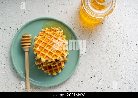 Selektiver Fokus, belgische Zuckerwaffeln mit Blumenhonig auf einem blauen Teller Stockfoto