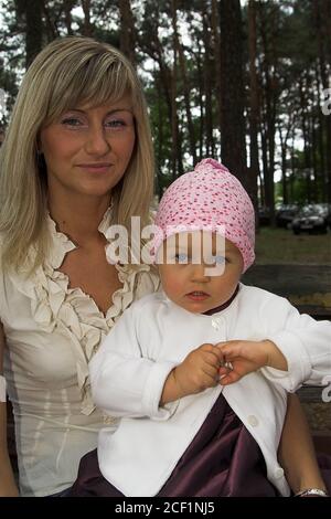 Mama mit einer kleinen Tochter auf ihrem Schoß. Mutter mit einer kleinen Tochter auf dem Schoß. Mama trzymająca córkę na kolanach. Kleines Mädchen auf ihrem Schoß. Stockfoto