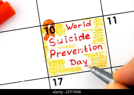Frau Finger mit Stift Schreiben Erinnerung World Suicide Prevention Day im Kalender. September 10. Stockfoto