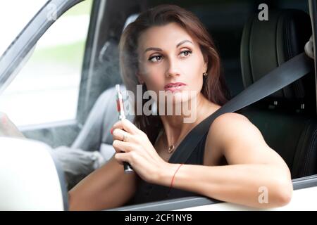 Hübsche Frau, die beim Autofahren die E-Zigarette raucht Stockfotografie