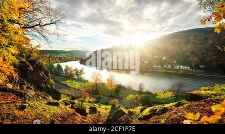 Blick auf den Neckar und idyllische Landschaft bei Heidelberg, Deutschland, denn an einem bunten Herbsttag geht die Sonne hinter einem Hügel unter Stockfoto