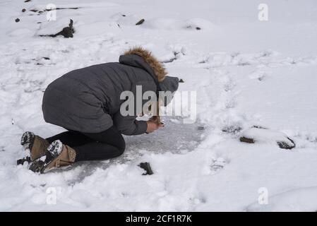 Teenager, die ein Foto mit ihrem Telefon aus gefrorenem Wasser Stockfoto