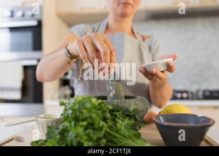 Frau kocht mit Mörser und Stößel in der Küche Stockfoto