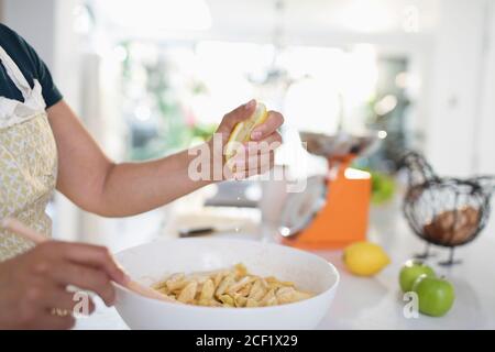 Frau quetscht Zitrone über geschnittene Äpfel in einer Schüssel Stockfoto