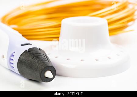 Nahaufnahme von bunt gerollten Kabeln und Kinder 3D-Druckstift isoliert auf weiß. Drei helle Filament Kunststoff liegen drinnen, Studio Hintergrund Stockfoto