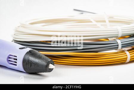 Nahaufnahme der Reihe von bunten gerollten Kabel und Kinder 3D-Druckstift isoliert auf weiß. Drei helle Filament Kunststoff liegen drinnen, Studio b Stockfoto