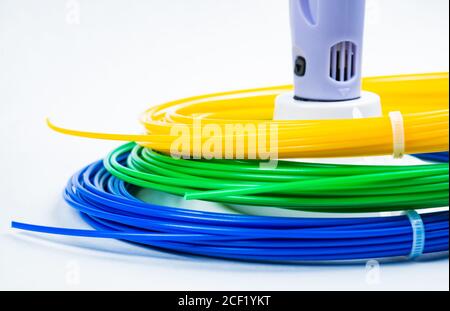 Nahaufnahme der Reihe von bunten gerollten Kabel um Kinder 3D-Druckstift isoliert auf weiß. Drei helle Filament Kunststoff liegen drinnen, studi Stockfoto