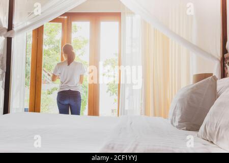 Asiatische Frauen im Hotelzimmer öffnen im Sommerurlaub das Fenster. Stockfoto