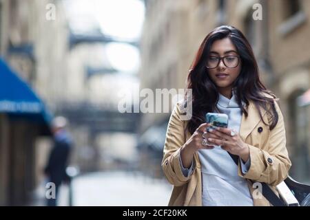 Frau, die Smartphone auf der Stadtstraße benutzt Stockfoto