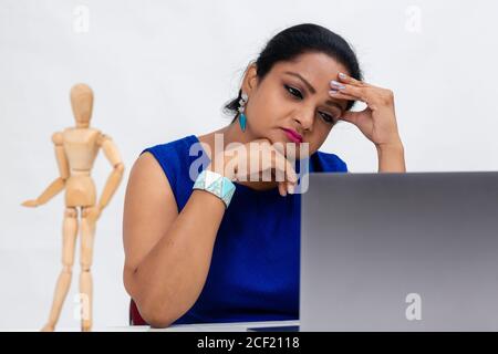 Müde indische Frau am Tisch, Freiberufler, Fernarbeit, Arbeit zu Hause, Online-Bildung, Büroarbeit zu Hause, in Gedanken verloren, müde und erschöpft. Stockfoto