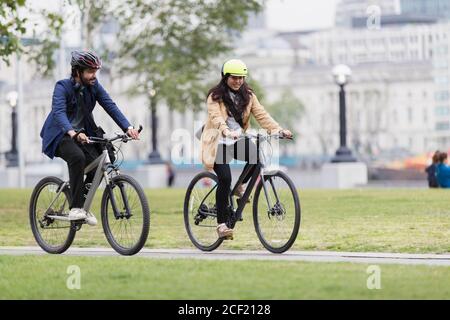 Geschäftsleute, die im Stadtpark Fahrrad fahren Stockfoto
