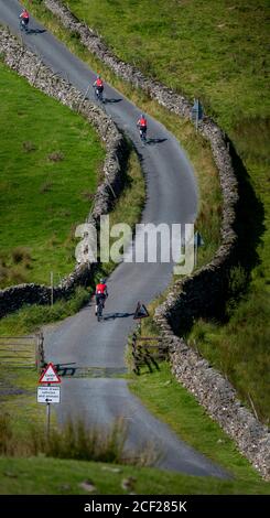 Mehrere Bilder von Radfahrerinnen, die auf ihrem Elektrofahrrad einen steilen Hügel im Yorkshire Dales Nationalpark, Großbritannien, erklimmen. Stockfoto