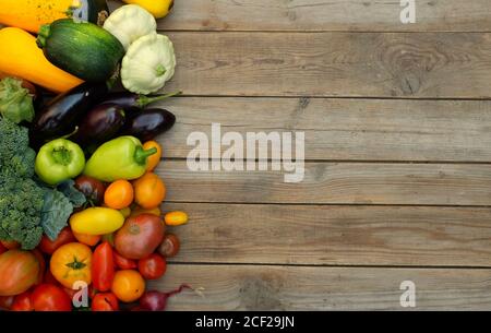 Viele verschiedene helle, bunte Gemüse auf einem hölzernen Hintergrund. Konzept für Ernte und Sommersaison. Stockfoto