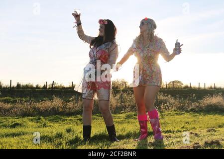 Fenwick, Ayrshire, Schottland, 24 Aug 2020 : Freunde Claire Stewart & Leona Young konnten Glastonbury dieses Jahr wegen der Coronvirus-Pandemie nicht machen, also beschlossen, ihr auf Mini-Festival zu haben. Mit Blumen im Haar, Gummistiefel an, Plastikmäntel durchschauen bei Regen tanzten die Mädchen zur Musik auf dem Handy. Modell Freigegeben Stockfoto