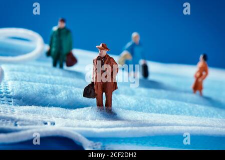 Einige Miniatur-Menschen auf einer blauen Einweg-Gesichtsmaske, die Konzepte wie zurück zur Arbeit oder Reisen während der covid-19 Pandemie Stockfoto