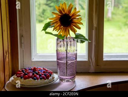 Tallinn, Harjumaa/ Estland-29AUG2020: Sammelgefäß Tarbeklaas namens Sammal mit Sonnenblume und Sommerkuchen auf Fensterbank. Stockfoto