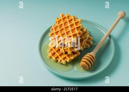 Selektiver Fokus, belgische Zuckerwaffeln mit Blumenhonig auf einem blauen Teller Stockfoto