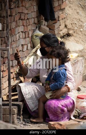 Dehradun, Uttarakhand/Indien- August 01 2020: Arme indische Frauen, die Selfie mit Baby machen, mit Maske wegen des pandemischen Corona-Virus covid-19. Stockfoto