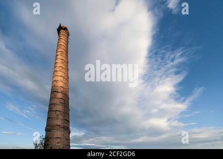 Ein alter Fabrikschornstein gegen einen wolkigen blauen Himmel Stockfoto