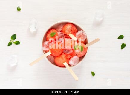 Gekühlte saftige reife süße Wassermelone auf einem Stock, natürliches Wassermelonensorbet mit Eis, sommerliches erfrischendes Dessert Stockfoto