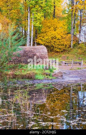 Grashütte an einem Waldsee mit Herbstfarben, Rekonstruktion aus der prähistorischen Zeit Stockfoto