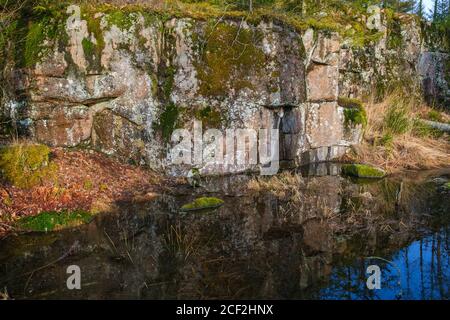 Felsklippe an einem Teich mit Reflexen im Wasser Stockfoto