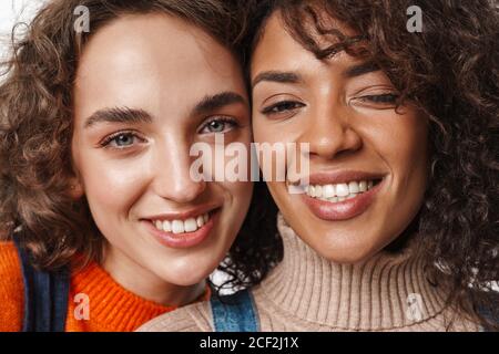 Nahaufnahme Foto von einem glücklichen positiv lächelnden multirassischen Mädchen Freunde isoliert über weiße Wand Hintergrund. Stockfoto