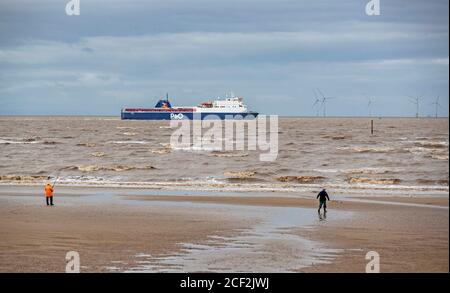 Die P&O Frachtschiffe MS Norbay fährt den Fluss Mersey entlang, vor Fischern am Strand von Crosby, Sefton in Merseyside. Stockfoto