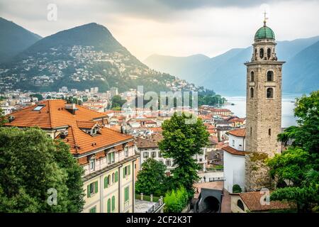 Landschaftlich reizvolle Stadtansicht von Lugano mit der Kathedrale von St. Lawrence Glocke Blick auf den Turm und den See und dramatisches Licht in Lugano Tessin Schweiz Stockfoto