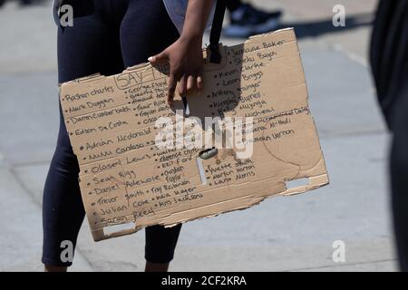 Ein Protestor, der ein Schild mit den Namen vieler schwarzer Menschen trägt, die durch die Polizei in den USA und Großbritannien in Black Lives Matter London getötet wurden Stockfoto