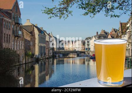 Ein Glas helles Bier am Kanal und an historischen Gebäuden in Gent, Belgien Stockfoto