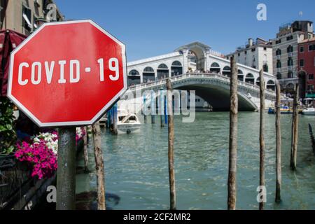 COVID-19 Schild mit Blick auf die Rialtobrücke am Grand Canal und Gondelboot in Venedig, Italien. Warnung vor einer Pandemie in Italien. Coronavirus-Krankheit. COVID Stockfoto