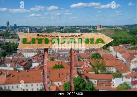 Holzpfeil Straßenschild mit Wort Litauen gegen Vilnius Altstadt Hintergrund. Reise nach Litauen Konzept. Stockfoto