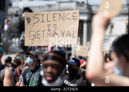Protestler mit einem Schild mit der Aufschrift "Silence is Verrat" bei einem Protest der Black Lives Matter am Trafalgar Square in London Stockfoto